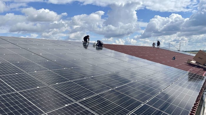 Arbeiter montieren und überprüfen Solarpanels auf einem großen Dach